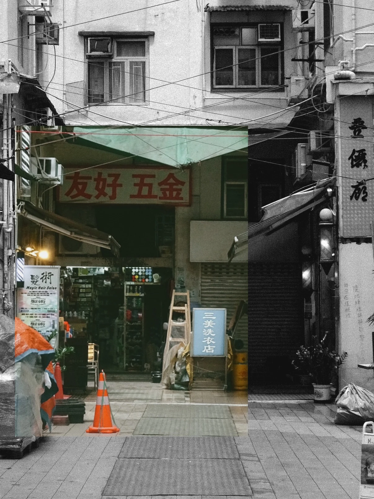 A hardware shop at the end of a Hong Kong side street, in black and white with a strip left in colour