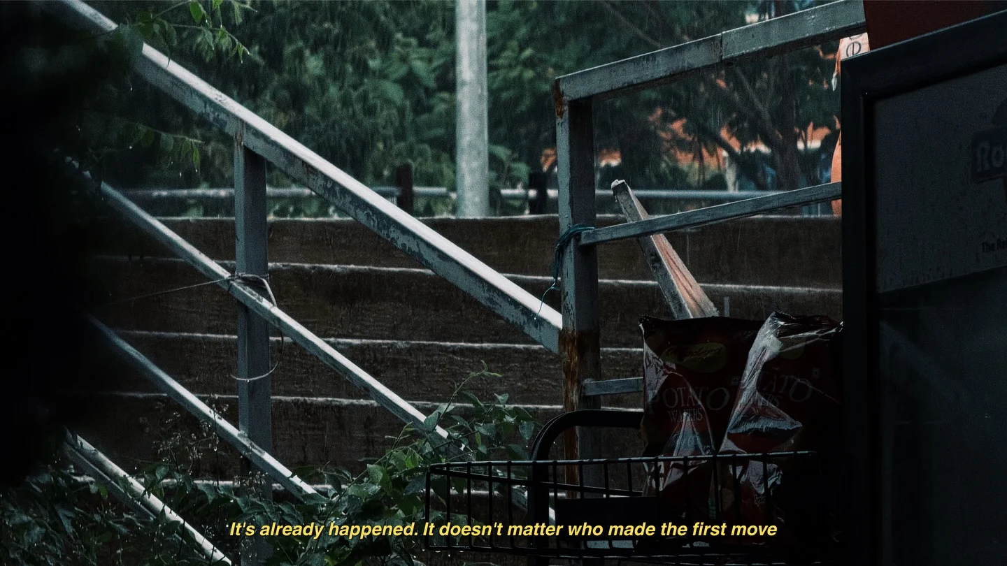Concrete stairs with metal railings in deep shade, with a yellow film subtitle along the bottom